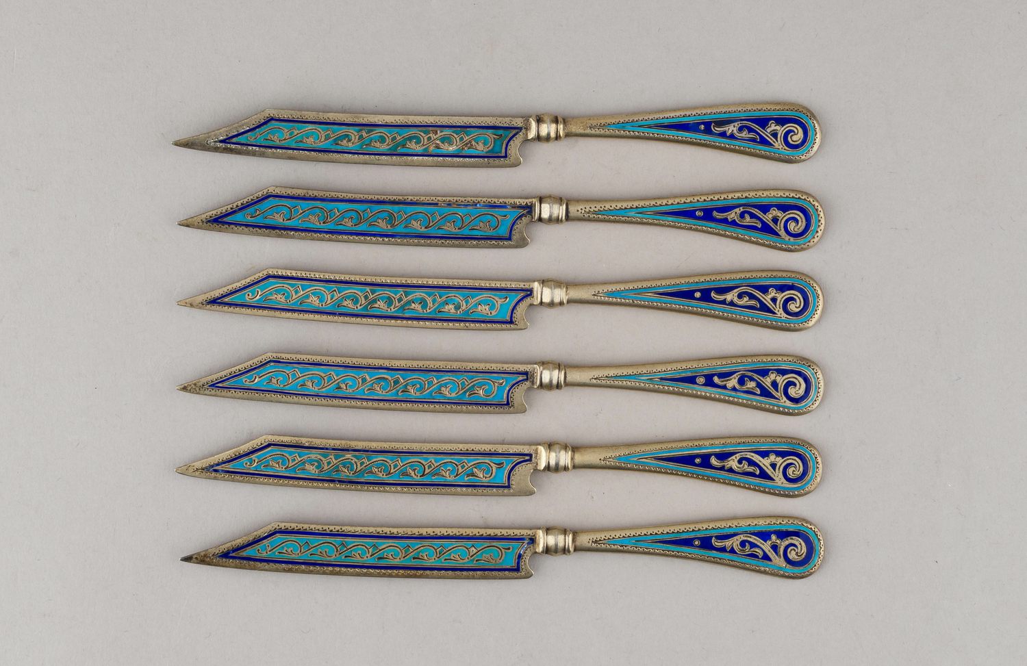 (Антип Кузмичев) Шесть десертных ножей с бирюзовой выемчатой эмалью.
Россия, Москва,  фабрика Кузьмичева Антипа,  1880-е годы.