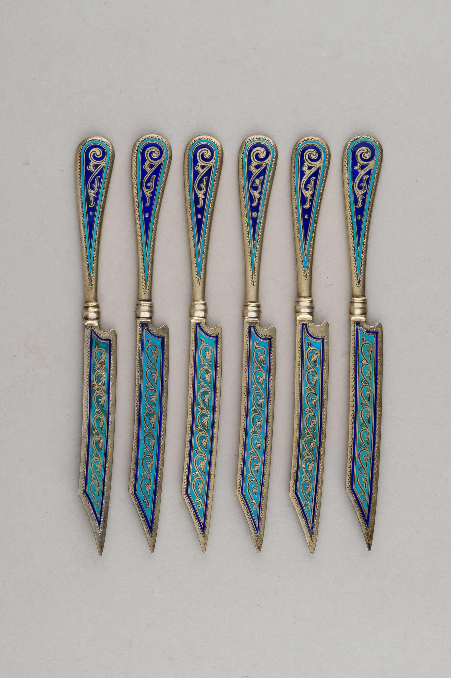 (Антип Кузмичев) Шесть десертных ножей с бирюзовой выемчатой эмалью.
Россия, Москва,  фабрика Кузьмичева Антипа,  1880-е годы.