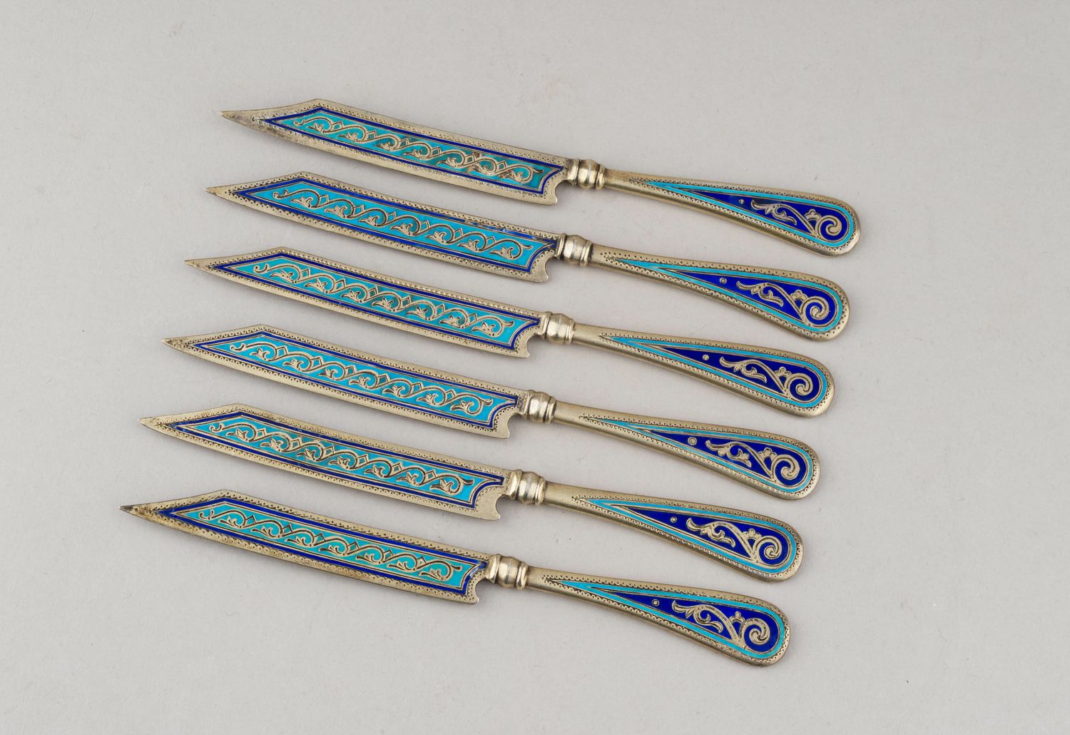 (Антип Кузмичев) Шесть десертных ножей с бирюзовой выемчатой эмалью.
Россия, Москва,  фабрика Кузьмичева Антипа,  1880-е годы.