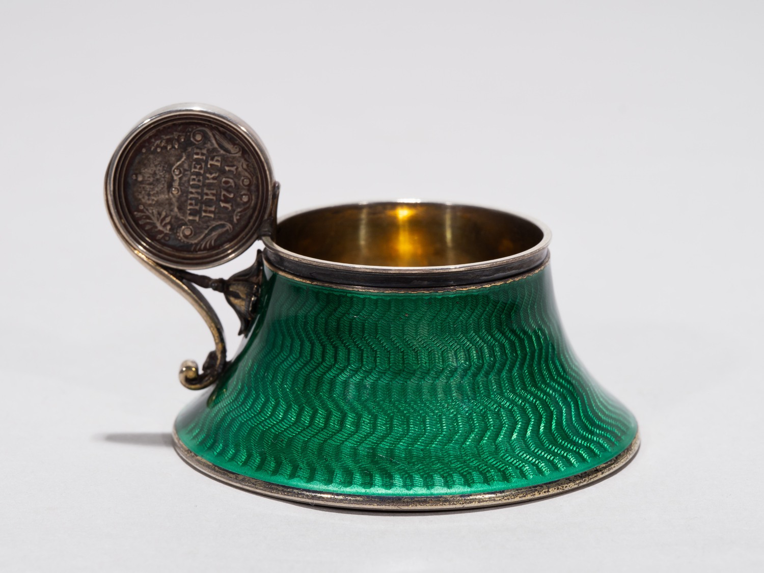 (Фаберже) Чарка изумрудной эмали гильоше с инкрустацией монетой 1791 года. 
Санкт-Петербург, фирма Фаберже, мастер Анна Ринге, начало XX в.