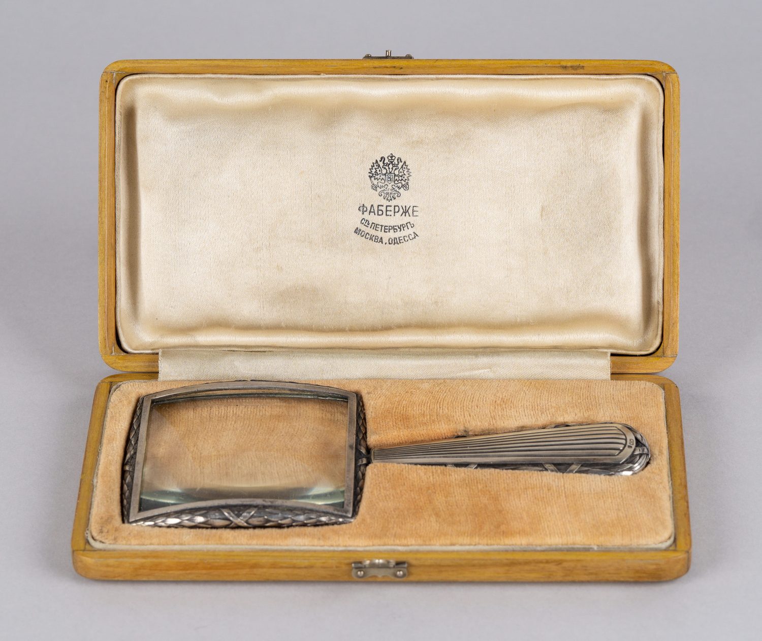 (Фаберже) Лупа в серебряной оправе с лавровыми листьями перетянутыми «ликторской связкой».
Россия, Санкт-Петербург, фирма Поставщика Высочайшего Двора К. Фаберже, мастер А.  Неваляйнен, 1908-1910-е годы.